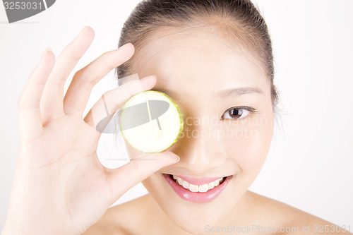 Image of Beautiful young Asian girl holding cucumber slice over face