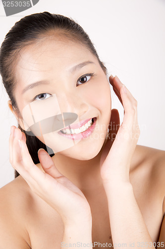 Image of Beautiful young Asian girl with both hands on face