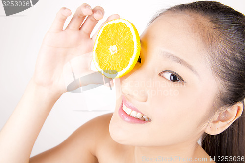 Image of Beautiful young Asian girl holding orange slice over face