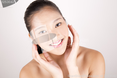 Image of Beautiful young Asian girl with both hands on face