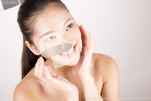 Image of Beautiful young Asian girl with both hands on face