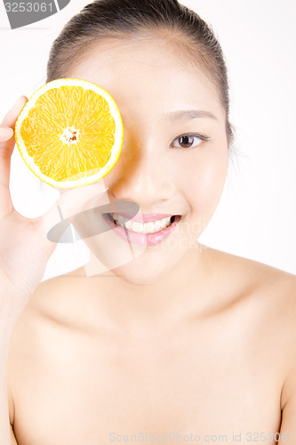 Image of Beautiful young Asian girl holding orange slice over face
