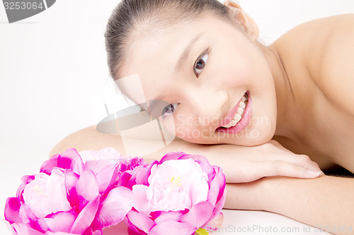 Image of Beautiful young Asian girl lying down with red peony flowers