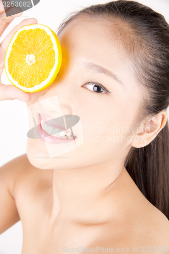 Image of Beautiful young Asian girl holding orange slice over face