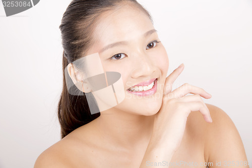 Image of Beautiful young Asian girl with one hand on face