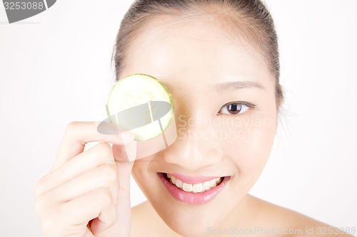 Image of Beautiful young Asian girl holding cucumber slice over face