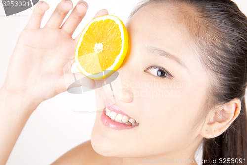 Image of Beautiful young Asian girl holding orange slice over face