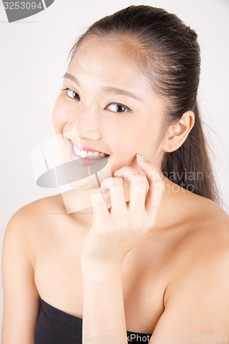 Image of Beautiful young Asian girl with one hand on face