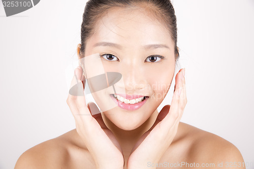 Image of Beautiful young Asian girl with both hands on face