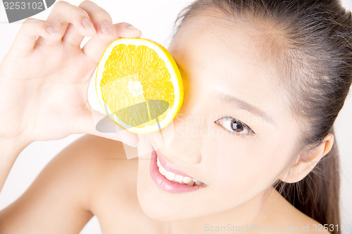 Image of Beautiful young Asian girl holding orange slice over face