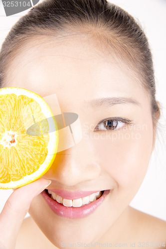 Image of Beautiful young Asian girl holding orange slice over face