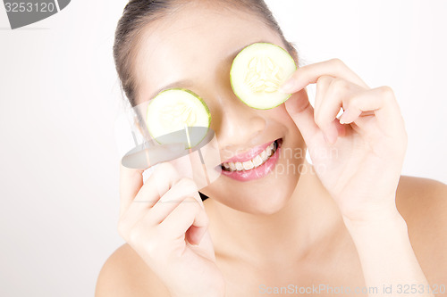 Image of Beautiful young Asian girl holding cucumber slice over face