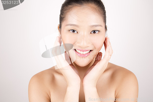 Image of Beautiful young Asian girl with both hands on face