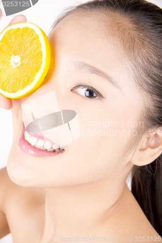 Image of Beautiful young Asian girl holding orange slice over face