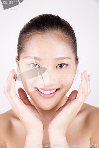 Image of Beautiful young Asian girl with both hands on face