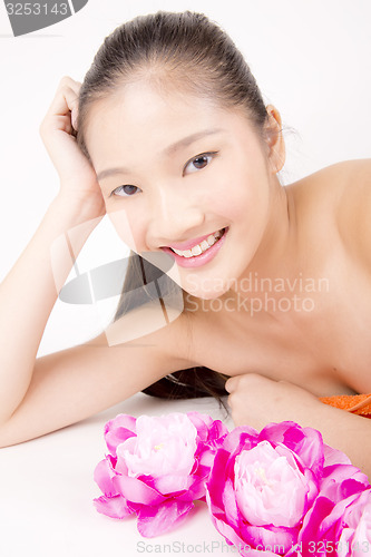 Image of Beautiful young Asian girl lying down with red peony flowers