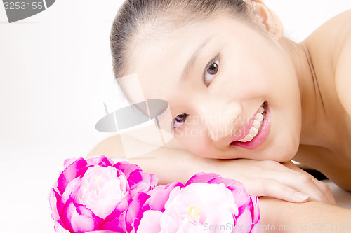 Image of Beautiful young Asian girl lying down with red peony flowers