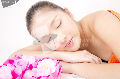 Image of Beautiful young Asian girl lying down with red peony flowers