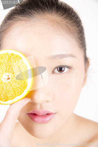 Image of Beautiful young Asian girl holding orange slice over face