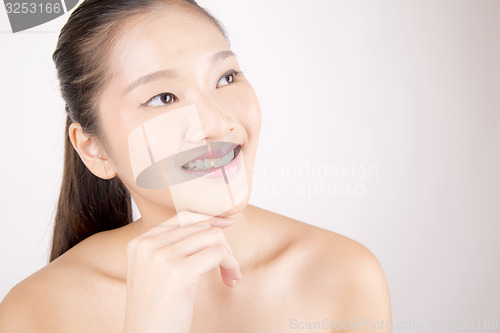 Image of Beautiful young Asian girl with one hand on face