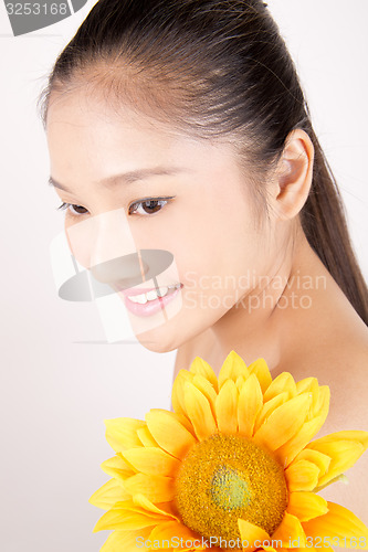 Image of Beautiful young Asian girl with bright yellow sunflower