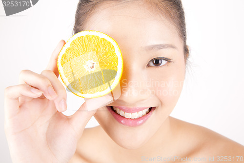 Image of Beautiful young Asian girl holding orange slice over face