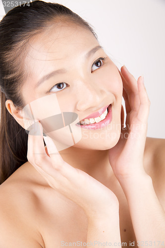 Image of Beautiful young Asian girl with both hands on face