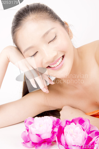 Image of Beautiful young Asian girl lying down with red peony flowers