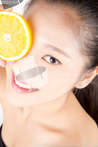 Image of Beautiful young Asian girl holding orange slice over face