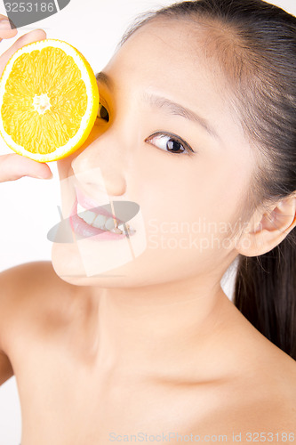 Image of Beautiful young Asian girl holding orange slice over face