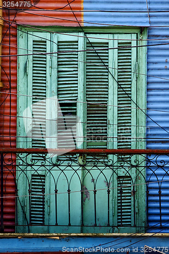 Image of green wood venetian blind and a red blue wall 