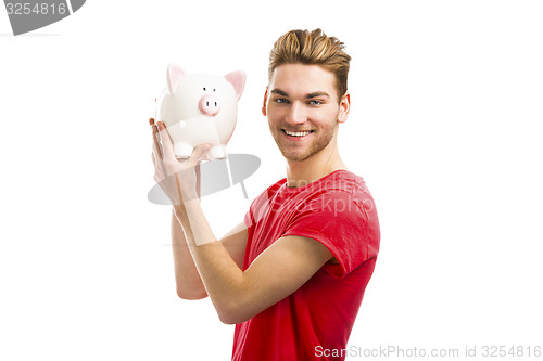 Image of Handsome young man holding a piggy bank