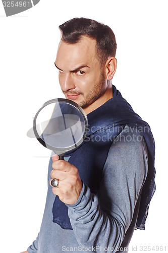 Image of Serious man looking through magnifying glass