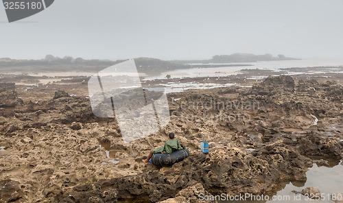 Image of sea gull flying across a rocky bottom during low tide