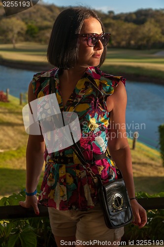 Image of Young woman in sunglasses enjoying summer breeze at beach. 