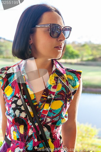 Image of Young woman in sunglasses enjoying summer breeze at beach. 