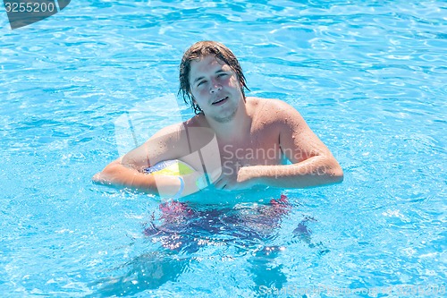 Image of Happy man with water ball in a swimming pool 