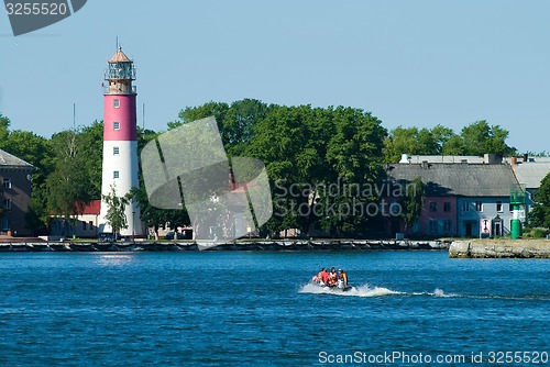 Image of People in rubber boat and lighthouse is Baltiysk