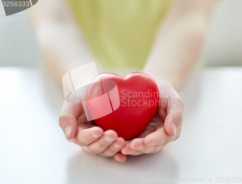 Image of close up of child hands holding red heart