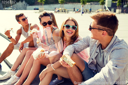 Image of group of smiling friends sitting on city square