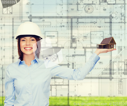 Image of businesswoman in helmet holding house on palm
