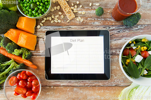 Image of close up of diet plan on tablet pc and vegetables