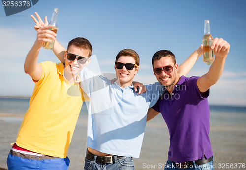 Image of happy friends with beer bottles on beach