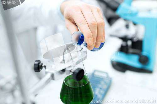 Image of close up of scientist filling test tubes in lab