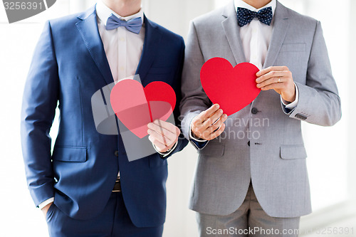 Image of close up of male gay couple holding red hearts