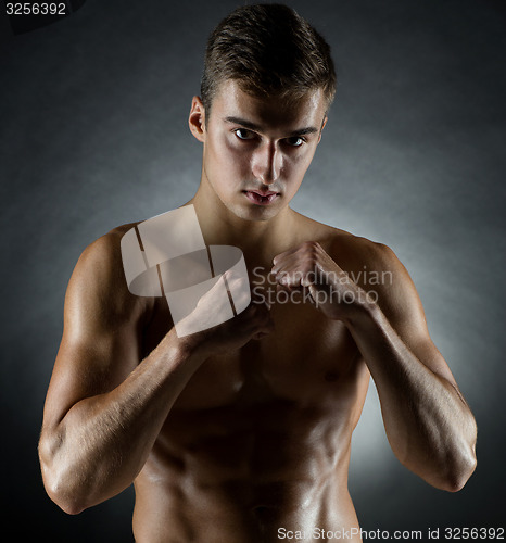 Image of young man on fighting stand over black background