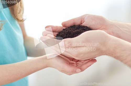 Image of close up of father and girl hands holding sprout