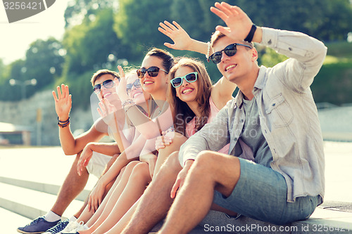 Image of group of smiling friends sitting on city street