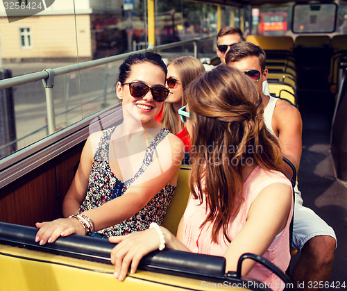 Image of group of smiling friends traveling by tour bus