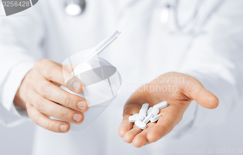 Image of doctor hands holding white pack and pills